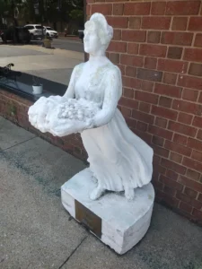 statue of a woman offering a basket of fruit.
