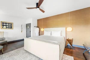 Modern bedroom featuring a white bed, warm wooden accents.