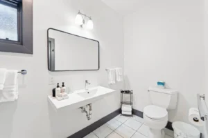 Bathroom with toilet, and black framed mirror.