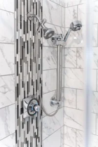 Shower with chrome fixtures and tiled wall