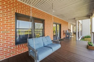 outdoor patio with a blue swing and wooden flooring.