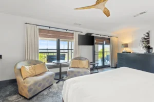 A Bedoom featuring a bed and several chairs, with a ceiling fan above.