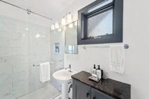 A bathroom featuring a sink and a shower, with tiled walls.
