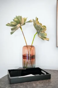 Vase with green leafy stems on a black table
