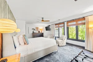 Bedroom with a king-sized bed, armchairs, and large windows.