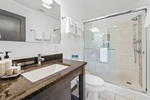 A bathroom featuring a shower and sink, with tiled walls, a countertop, and a mirror.