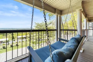 A porch swing hangs beside a couch on a deck.
