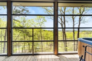 A room with large glass windows overlooking a lush outdoor area.
