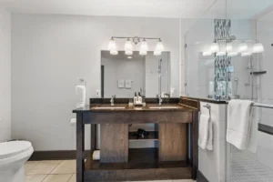 A bathroom vanity with a double sink, large mirror, and light fixture.