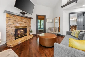 Deep Woods Cottage living room with stone fireplace and modern seating.