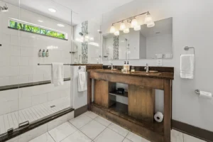 Deep Woods Cottage bathroom with double sink vanity and glass shower.