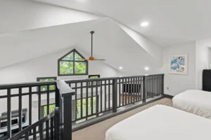 Deep Woods Cottage Bedroom with two white beds, black railing, pillows, and styled walls.