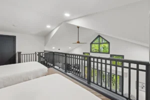 A bright loft space with a black railing overlooking a lower level.