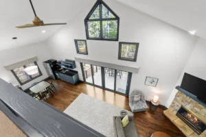living area with high vaulted ceilings, a ceiling fan, large triangular window, and multiple smaller windows