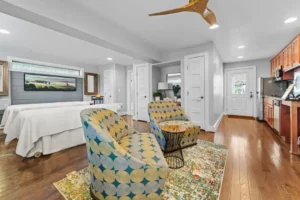A room featuring two chairs on a wood floor, with a ceiling fan above and various interior design elements present.