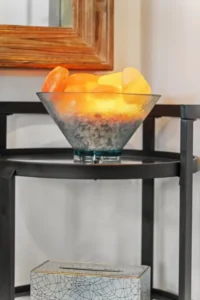 A glass bowl filled with glowing orange and yellow stones sits atop a black table, adding warmth to the room's decor.