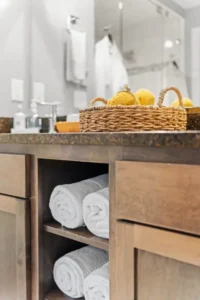 Spa bathroom with rolled towels, bath bombs in a basket, and wooden vanity.